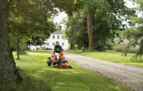 Kvinna som klipper gräset med en batteridriven Husqvarna Rider